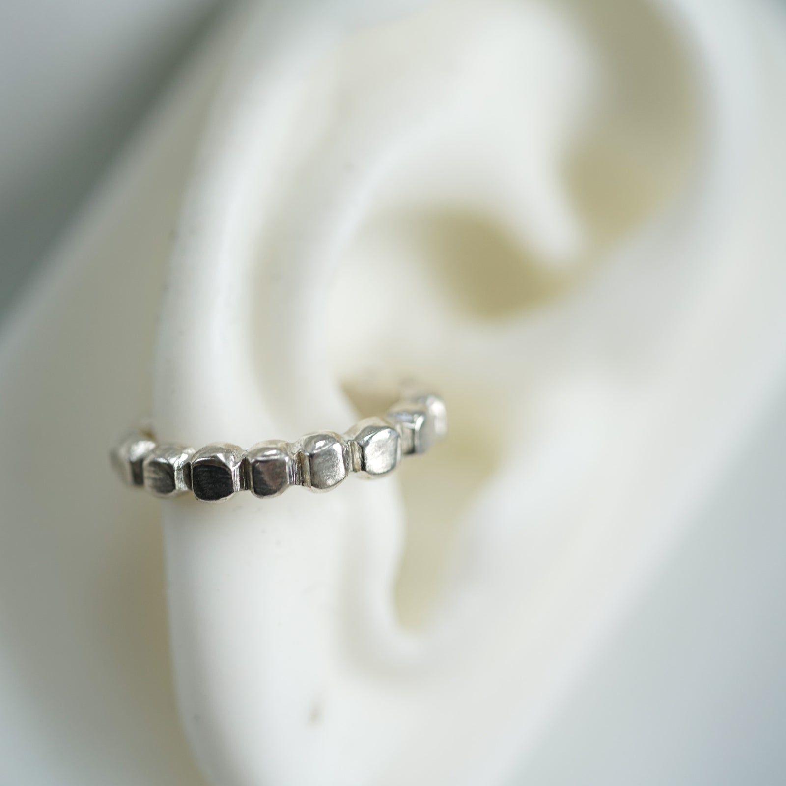 ACFJ silver ear cuff with dots on a ear