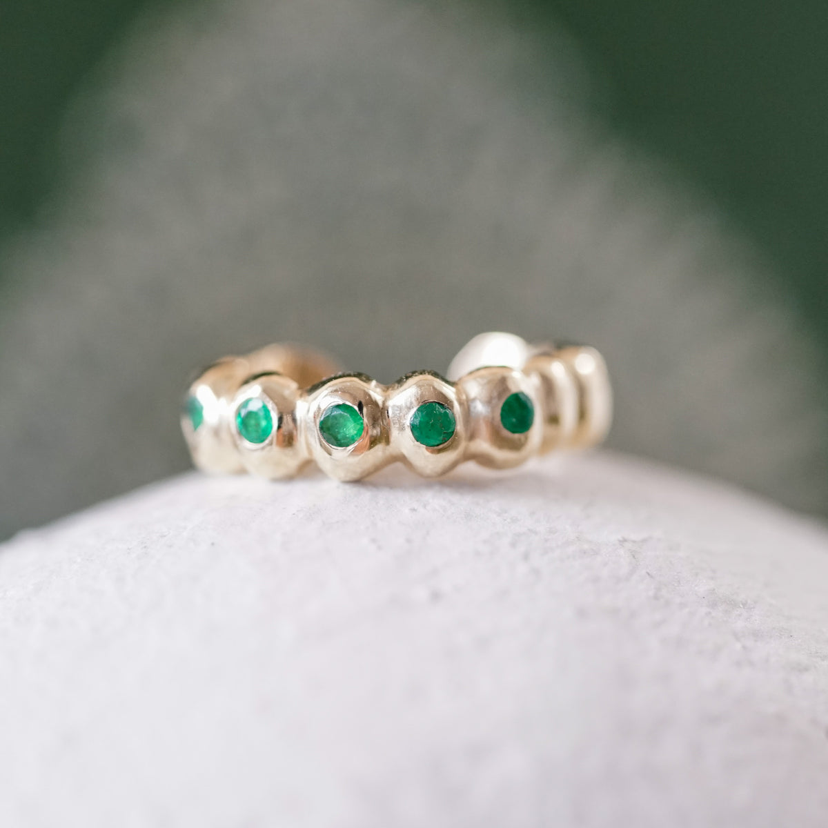 gold ear cuff with emeralds on a white surface