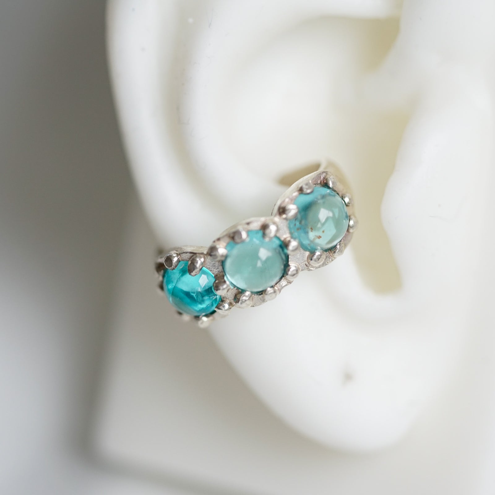 acfj silver ear cuff with blue topaz cabochons on a ear lobe