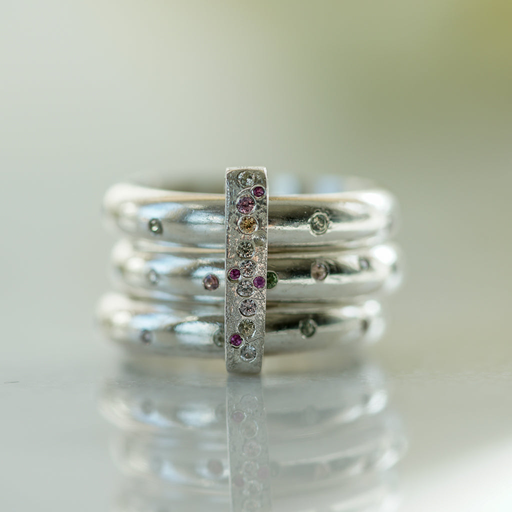 3 rings in sterling silver flush set with multicolor sapphires with a ring connecting them