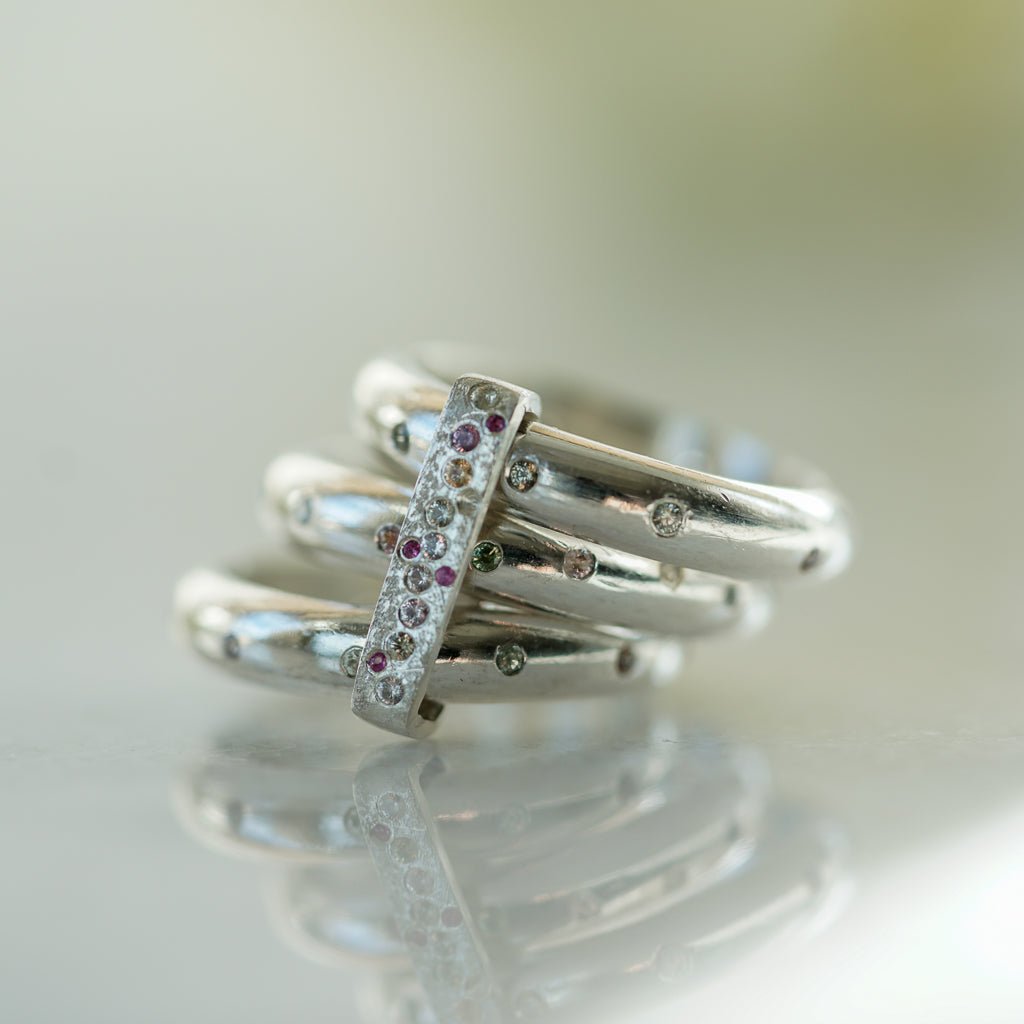 3 rings in sterling silver flush set with multicolor sapphires with a ring connecting them