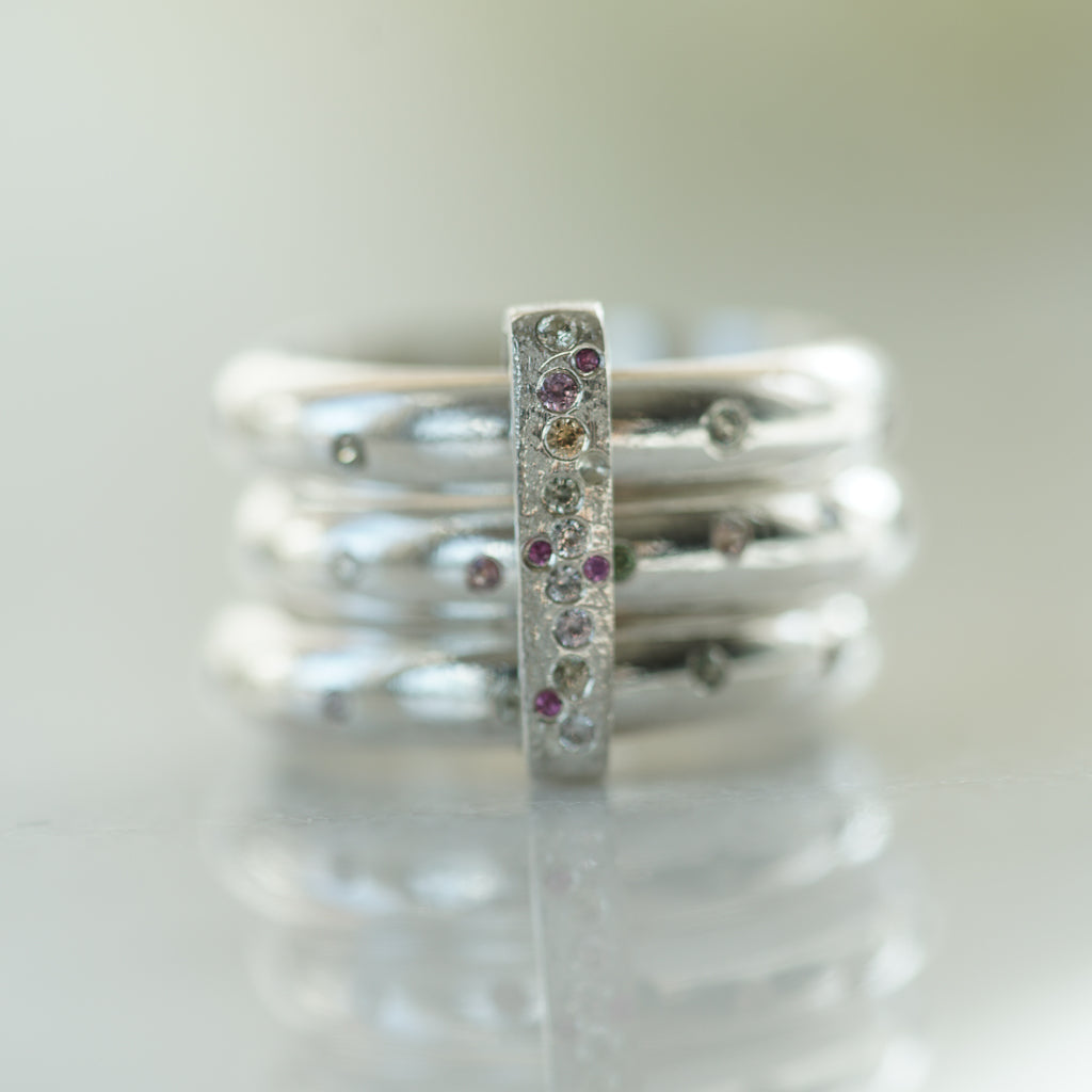 3 rings in sterling silver flush set with multicolor sapphires with a ring connecting them